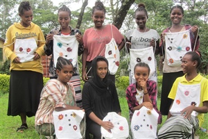 Stolz zeigt eine Frauengruppe ihre selbst angefertigten Stoffrucksäcke.